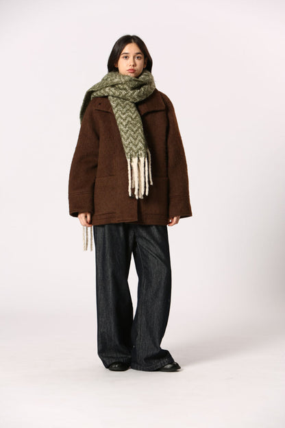 Écharpe verte à motif chevron avec franges blanches, portée sur manteau brun