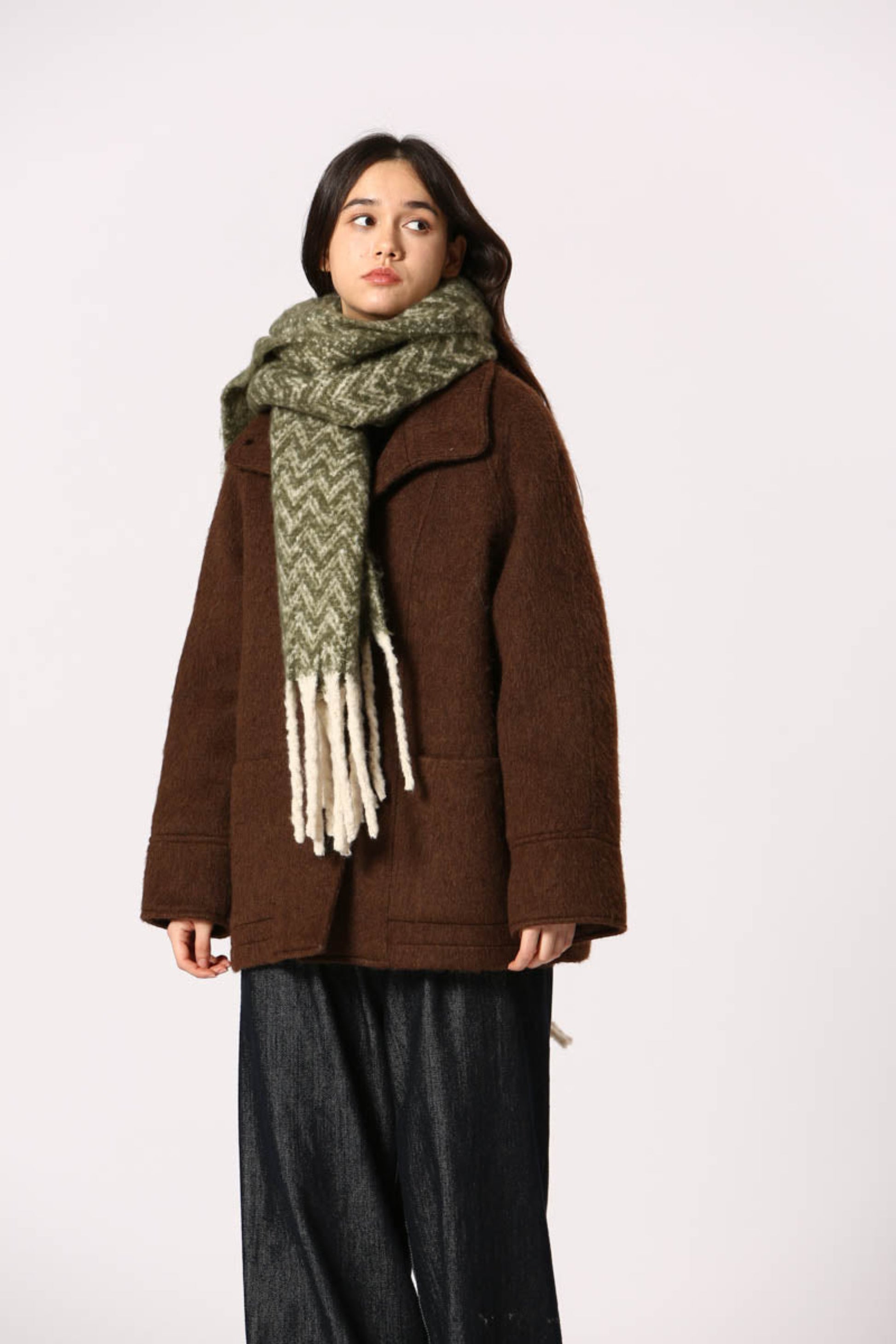 Écharpe verte à motif chevron avec franges blanches, portée sur manteau brun