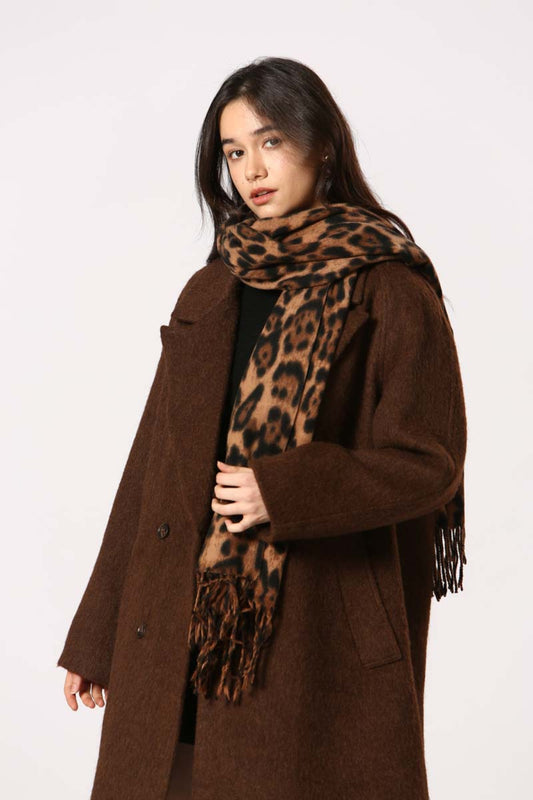 Femme portant l’écharpe Kylie brun léopard avec un manteau marron, détail franges visibles