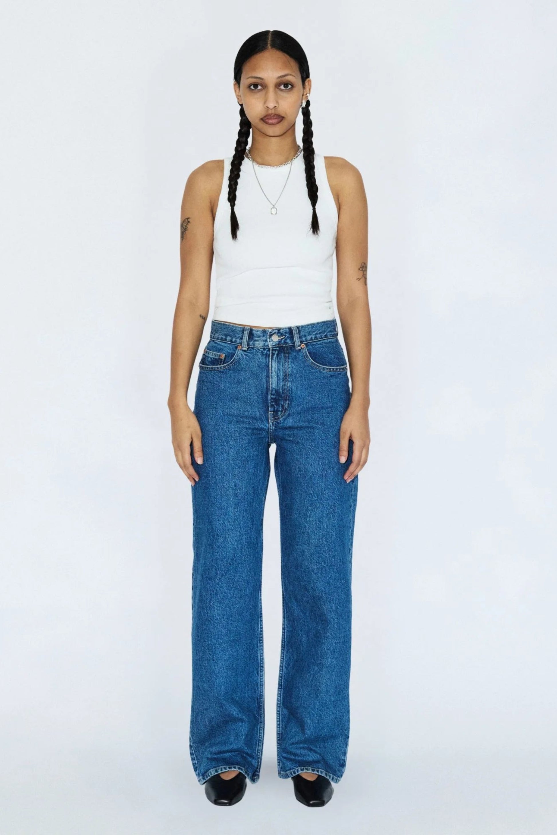 Femme portant le jeans Echo bleu denim rétro avec un haut blanc, coupe droite, taille haute et style vintage.