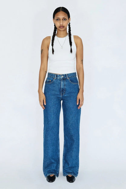 Femme portant le jeans Echo bleu denim rétro avec un haut blanc, coupe droite, taille haute et style vintage.