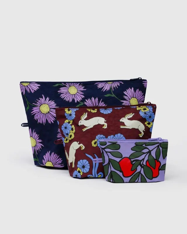 Trois pochettes nylon recyclé motifs colorés, alignées debout pour montrer leur format