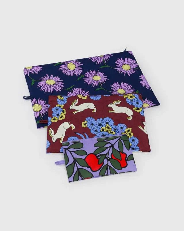 Ensemble de trois pochettes avec motifs fleurs, lapins et pommes, vues à plat sur fond neutre
