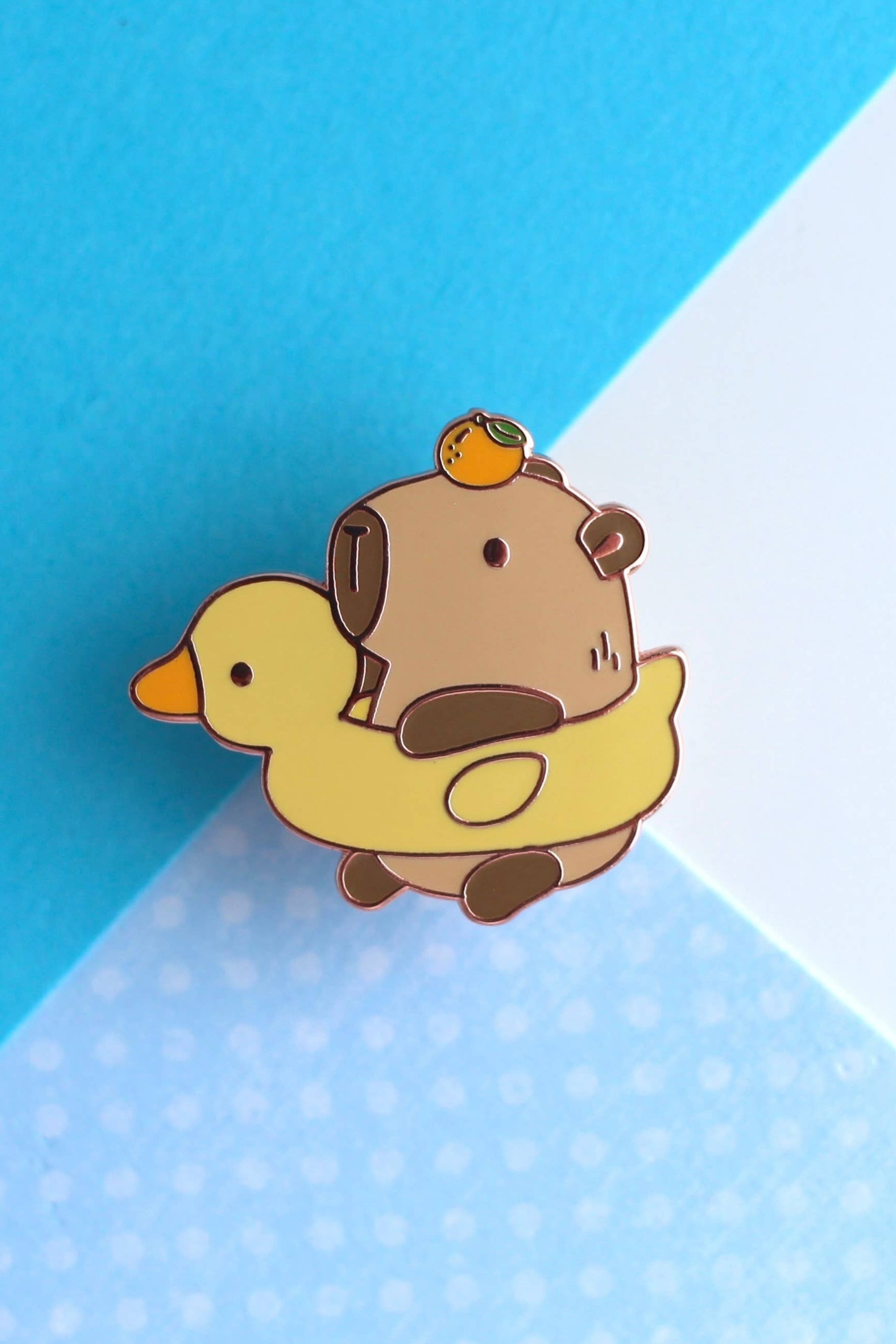 Gros plan sur l’épinglette Capybara et Canard en émail dur plaqué cuivre, design mignon et brillant.