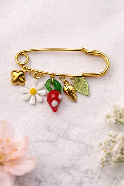 epinglette doree avec charms fleur blanche piment rouge et feuilles vertes sur fond neutre + bijou fantaisie colore et original