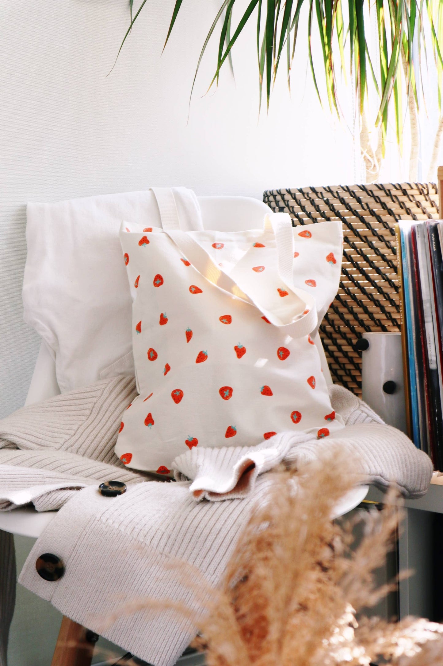 Sac fourre-tout crème motif fraises posé sur un fauteuil – sac écologique en lin et coton.