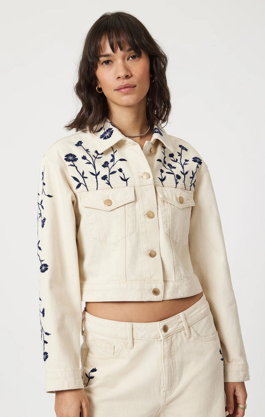 Zoom sur le haut de la veste en denim beige avec broderies florales bleues – coupe courte