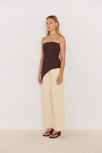 Vue de profil du haut asymétrique en maille chocolat porté avec un pantalon clair