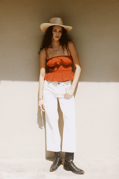 Look complet avec haut smocké rouge, pantalon blanc et bottes noires