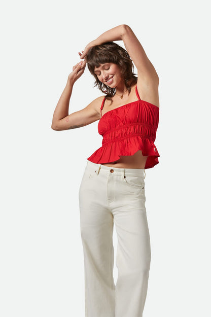 Femme souriante portant le haut rouge, bras levés, sur fond blanc