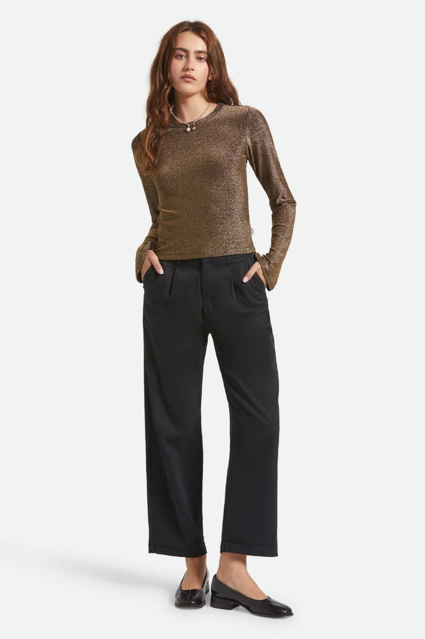 Vue complète haut Donna doré manches longues porté avec un pantalon à jambe droite bleu marine.