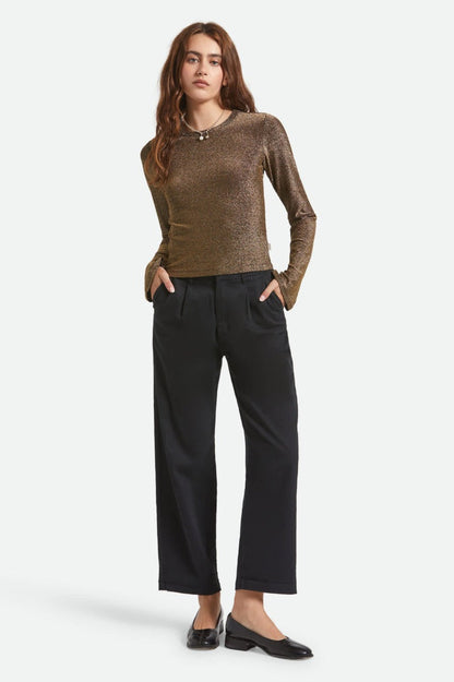 Vue complète haut Donna doré manches longues porté avec un pantalon à jambe droite bleu marine.