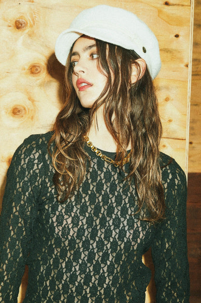 Haut Mathilda en dentelle noire porté avec chaîne dorée et chapeau blanc