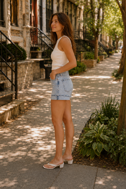 Short Heidi Bleu porté de côté avec camisole blanche, coupe taille haute et revers style années 90.