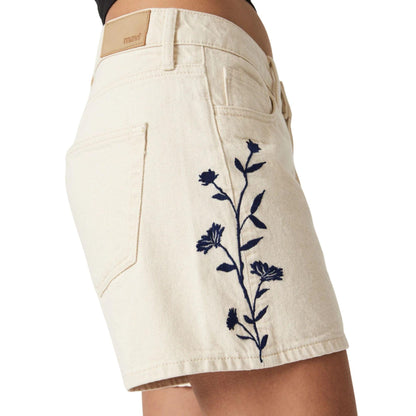 Détail de la broderie florale bleue sur le côté du short en denim beige
