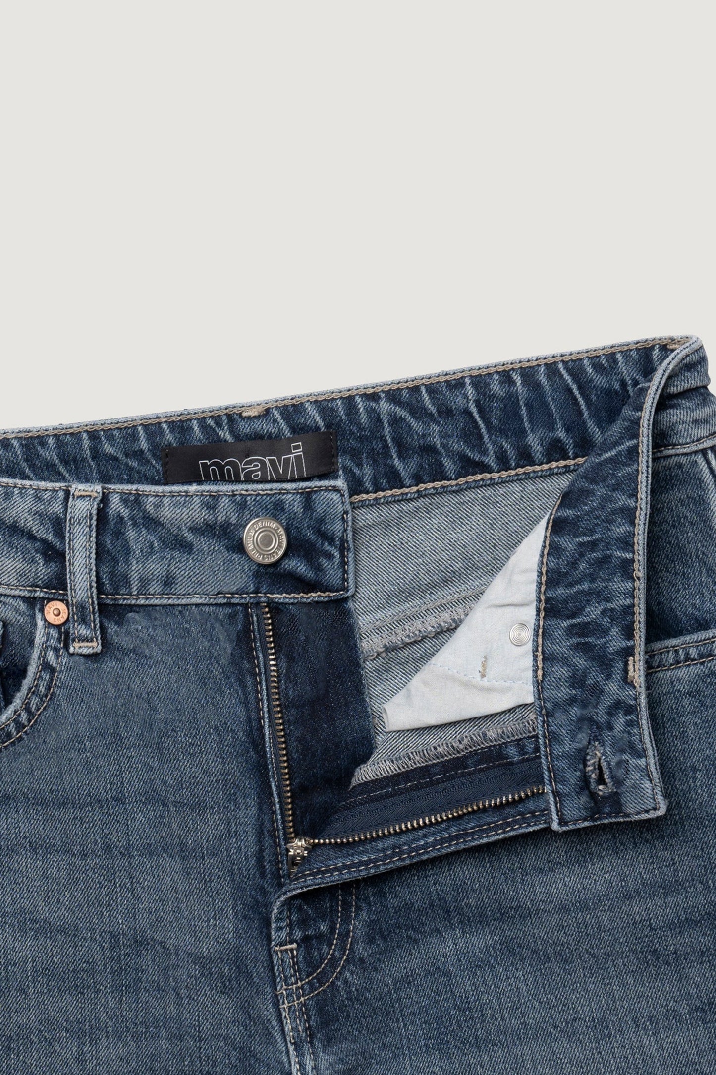 Détail du jean Mavi New York bleu classique avec bouton gravé et braguette ouverte.