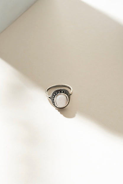 Bague en argent sterling avec pierre de lune posée sur fond crème