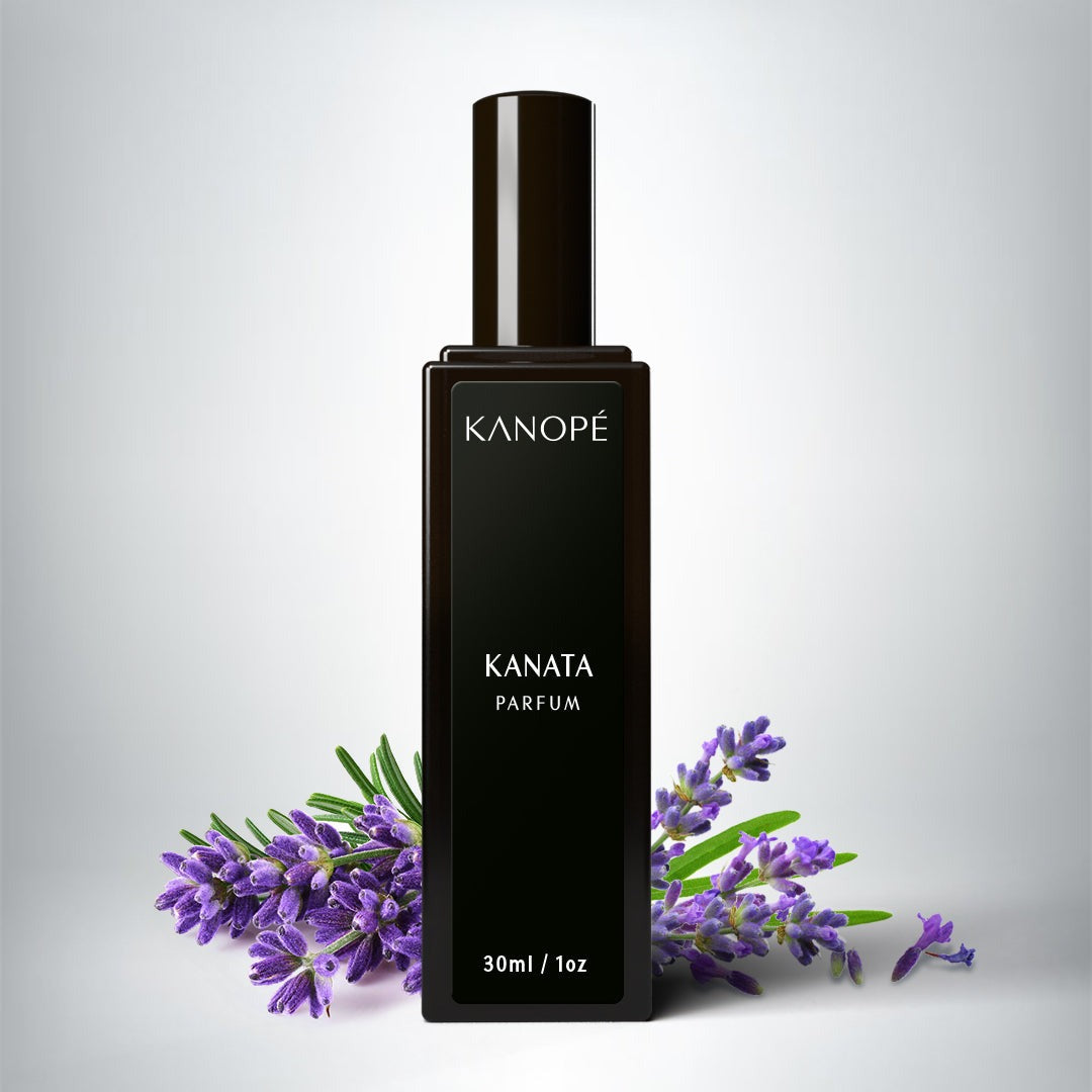 Le parfum est présenté dans une petite bouteilles rectangle en verre noir. Une étiquette noire est collé sur le long de la bouteille. On peut lire Kanata et en en-dessous eau de parfum. On peut voir des branches de lavande de chaque côté de la bouteille. L'arrière plan est un fond blanc.