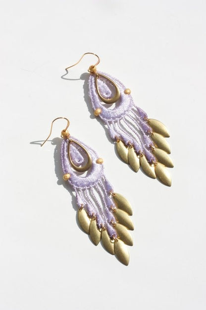 Paire de boucles d’oreilles Koila posées sur fond blanc – broderie lavande et pendentifs dorés