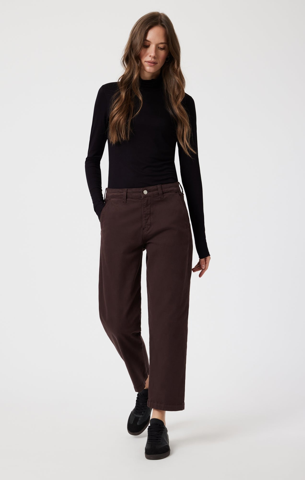 Pantalon de type chino à jambes droites en coton de couleur violet très foncé qui tend vers le marron. Le modèle le porte avec un col roulé noir et des chaussures fermées noires.