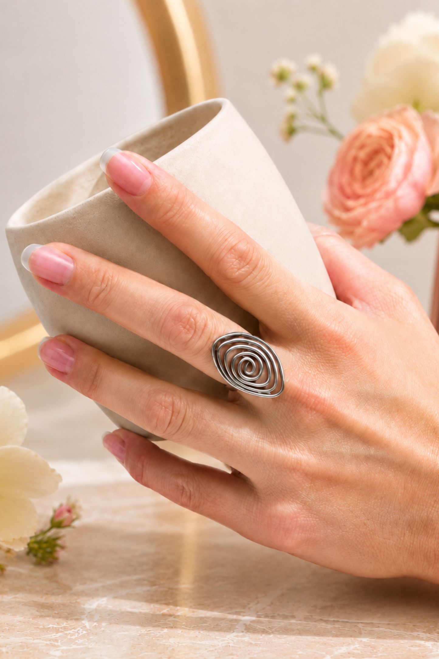 Bague Lilia argentée portée avec une tasse, style chic et délicat.
