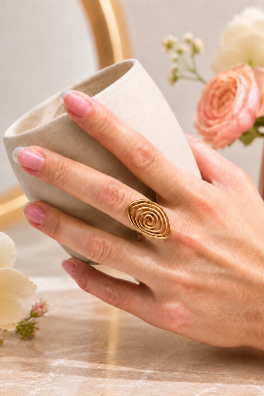 Bague Lilia dorée portée avec une tasse, mise en scène douce et féminine.