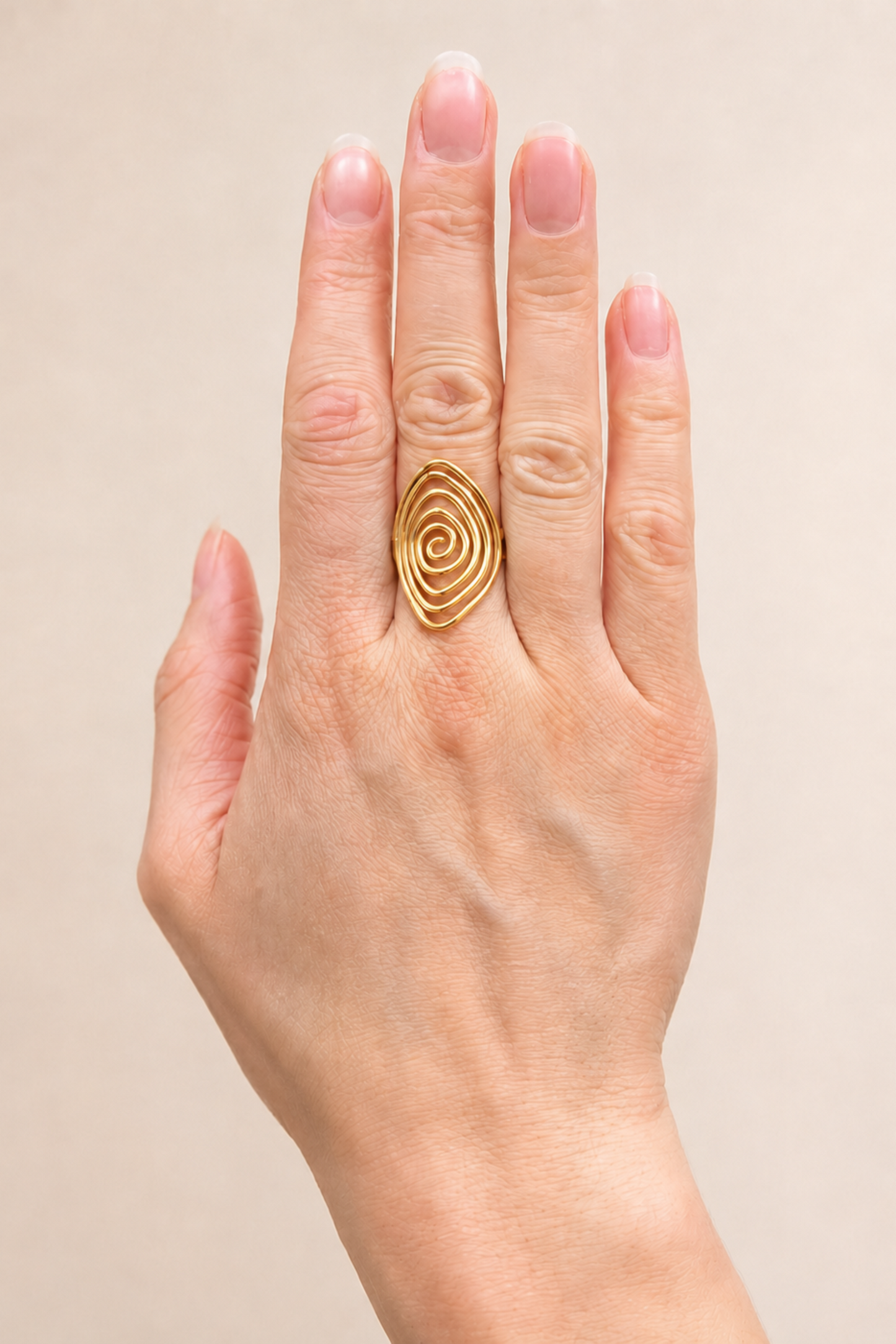 Bague Lilia dorée portée sur la main, avec fini brillant et motif spirale élégant.