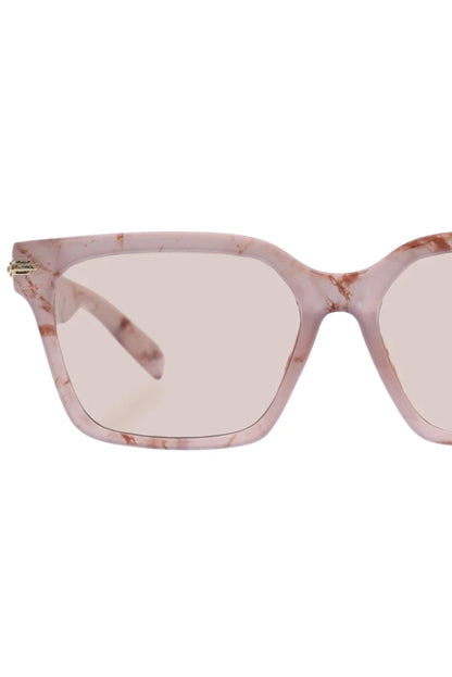Vue rapprochée des lunettes de soleil Maya Marbre Brumeux, monture carrée transparente rose et verres teinte orge.