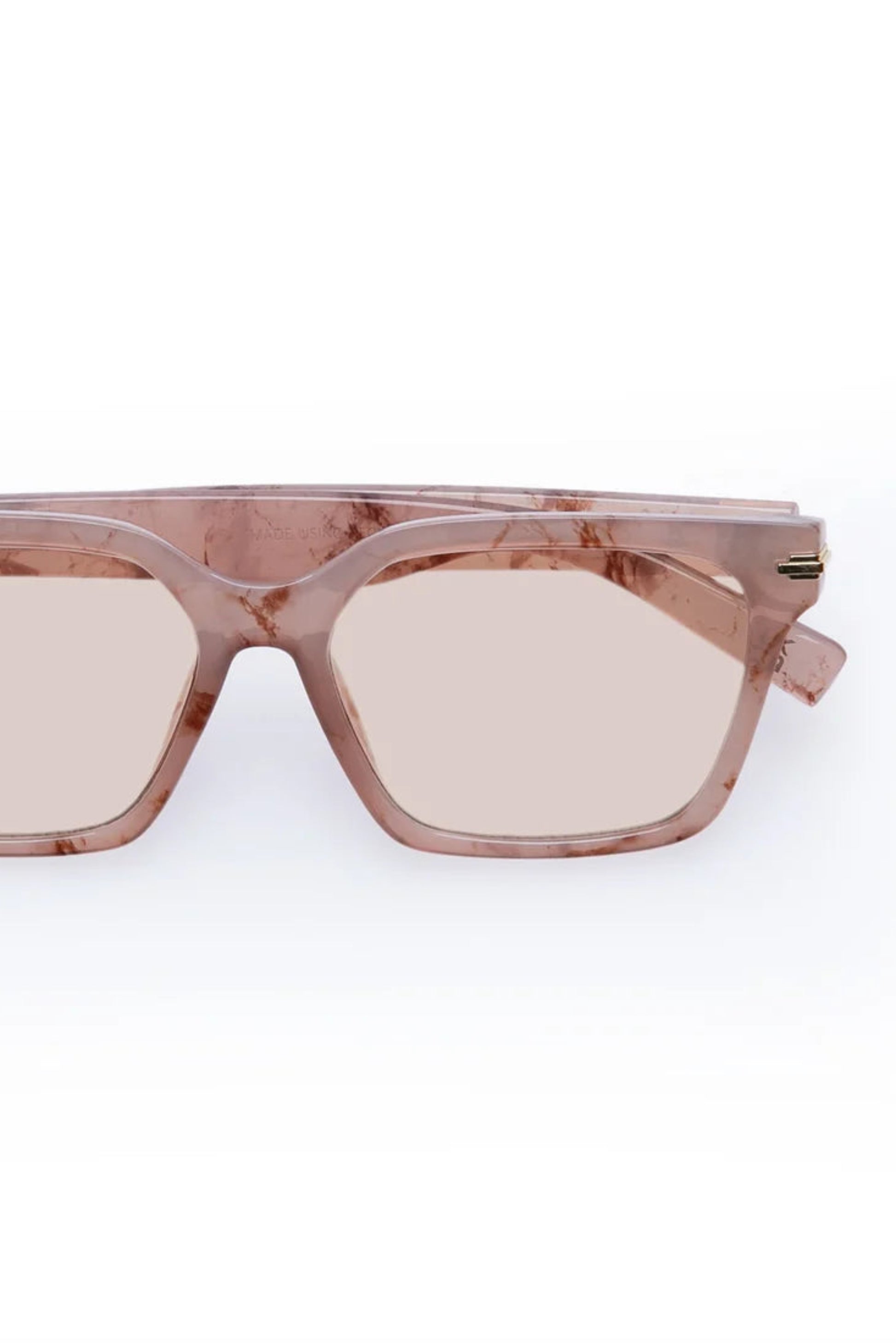 Vue de face des lunettes de soleil Maya Marbre Brumeux avec monture carrée rose marbrée et verres légèrement teintés.