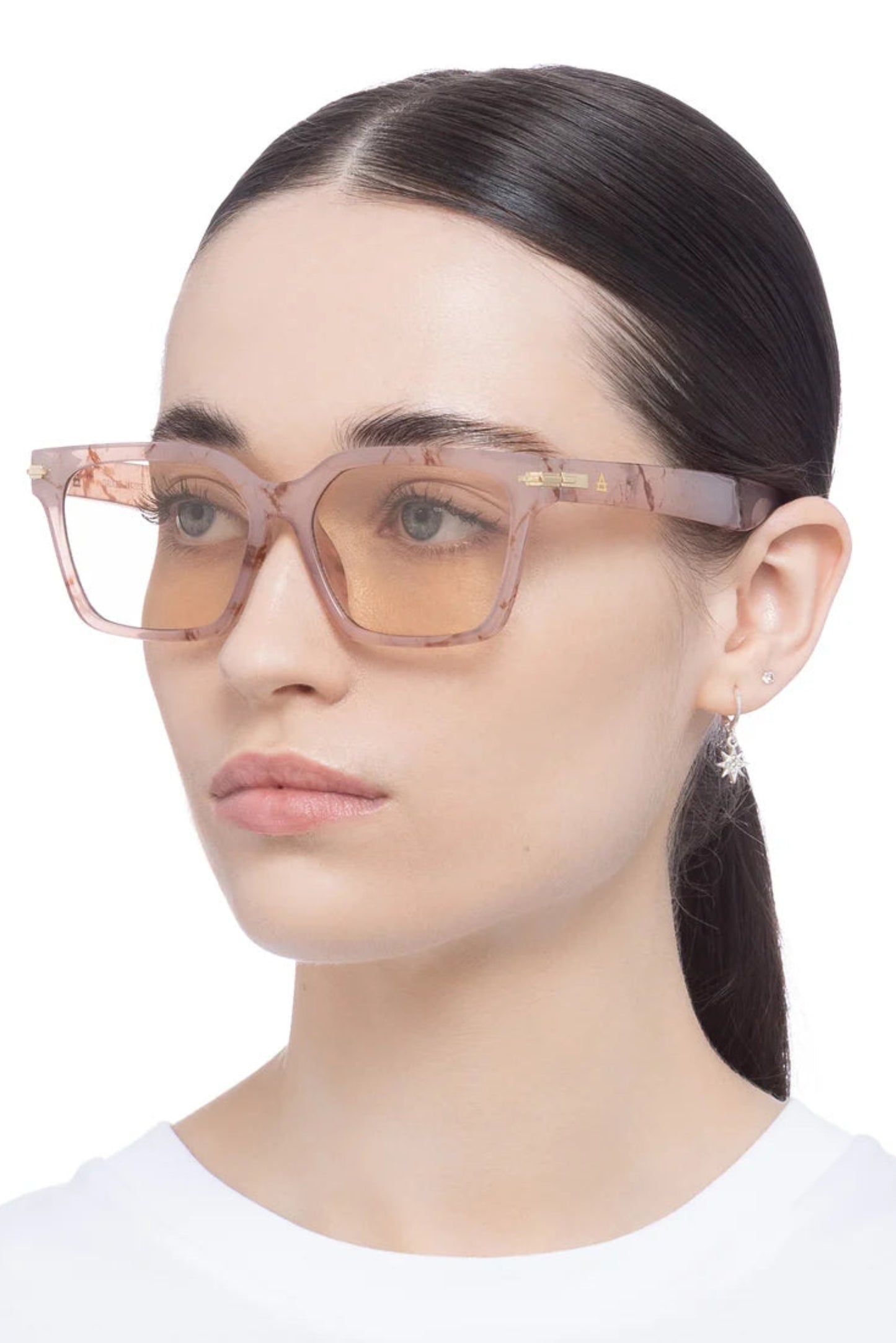 Lunettes de soleil Maya Marbre Brumeux portées par une femme, avec design carré unisexe et monture effet marbre rose.