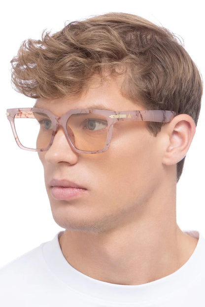 Lunettes de soleil Maya Marbre Brumeux portées par un homme, avec monture carrée rose marbrée et verres teinte orge.