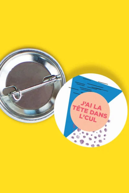 Macaron illustré avec message drôle J’ai la tête dans l’cul sur fond jaune.