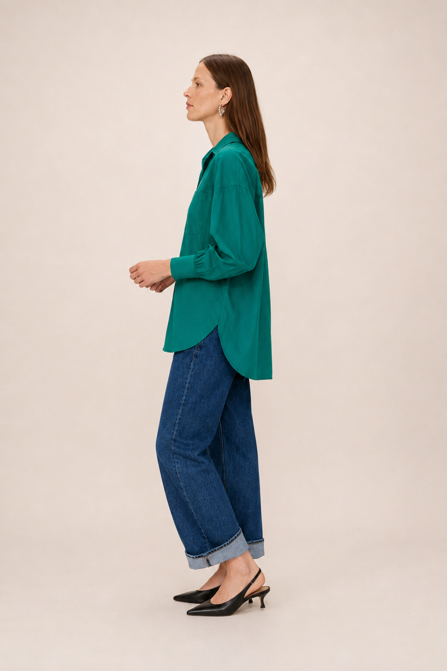 Chemise longue oversize verte portée de côté avec un jean large et une coupe fluide.
