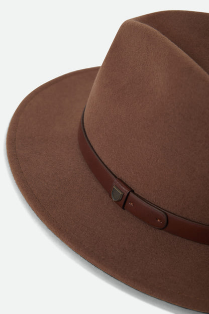 Détail du chapeau Messer sépia avec feutre de laine, bracelet en similicuir et épingle métallique.