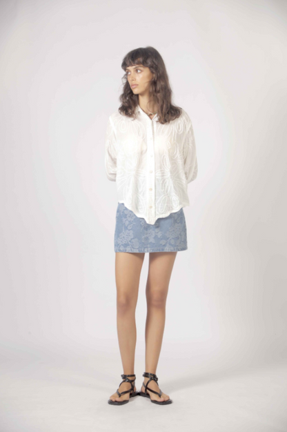 Chemise blanche brodée portée avec mini jupe en denim pâle