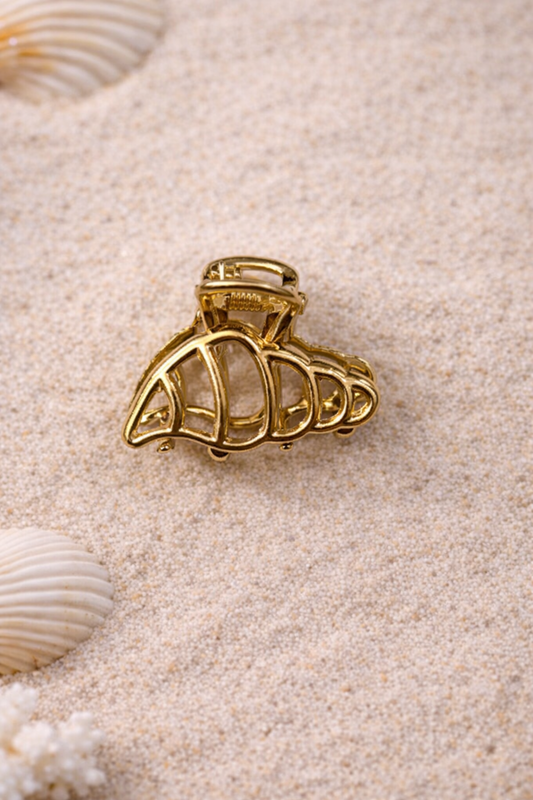 mini pince doree forme coquillage ajoure sur fond sable + style estival chic