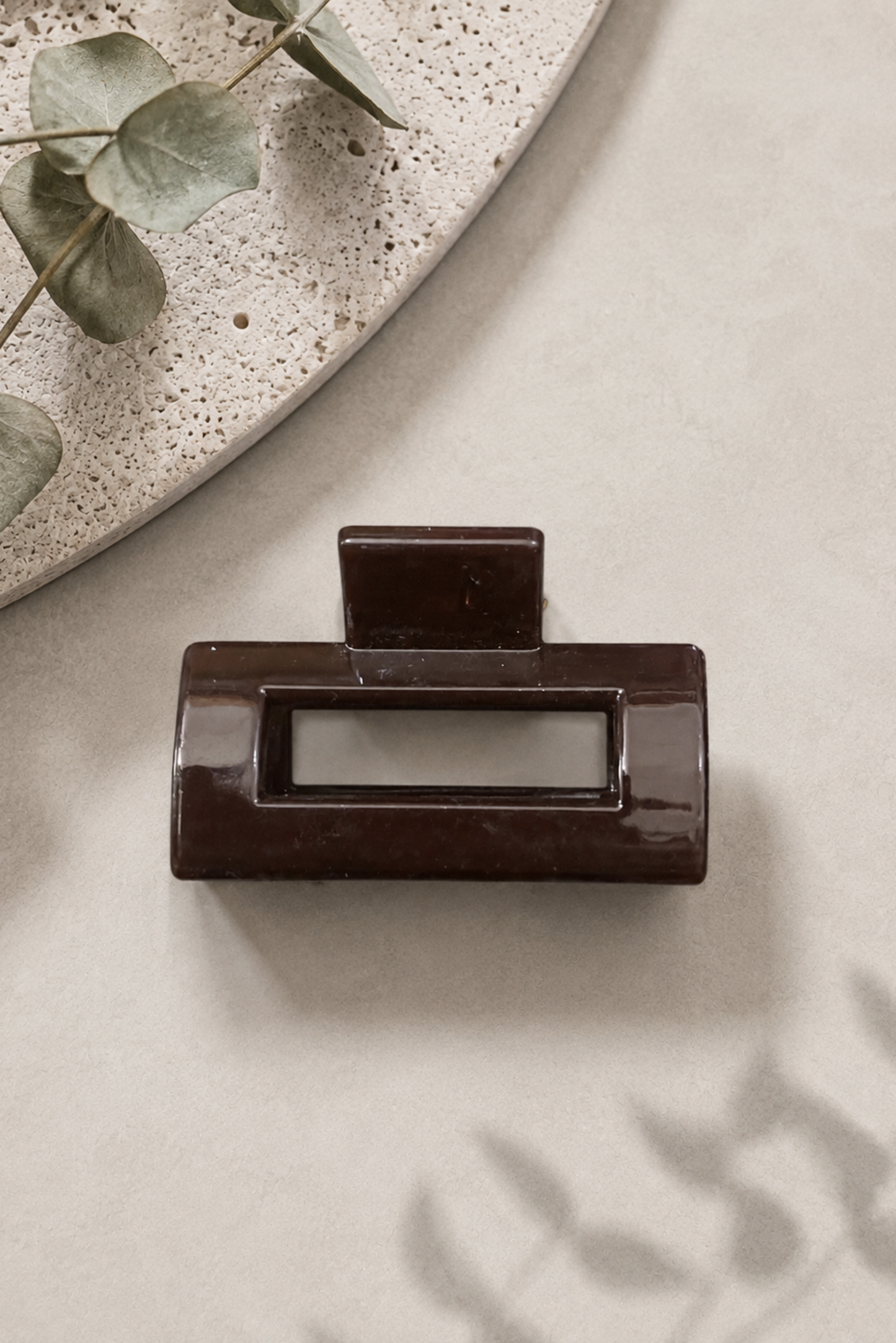Mini pince rectangle brun foncé avec fini brillant, parfaite pour une attache discrète et élégante.