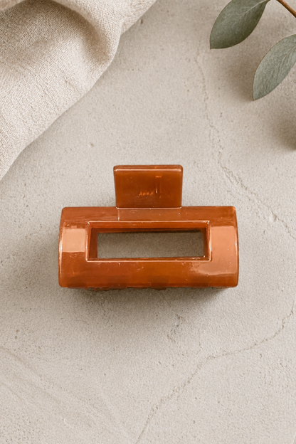 Mini pince rectangle caramel présentée sur fond beige avec forme géométrique et finition brillante.