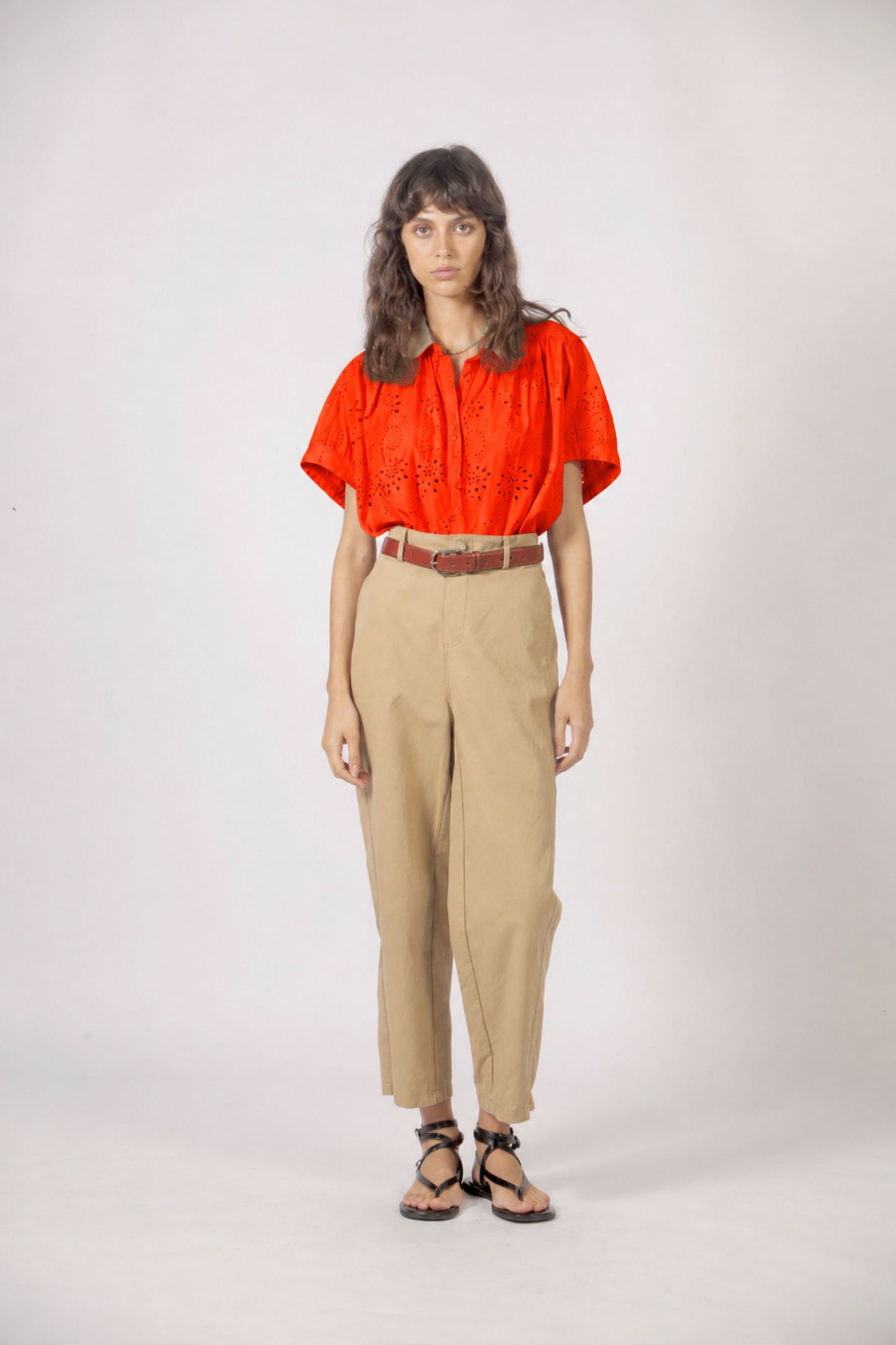 Haut Molly orange en coton brodé porté avec pantalon beige et ceinture pour un look bohème chic.