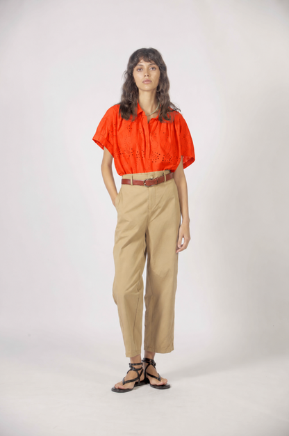 Haut Molly orange porté de face avec manches courtes amples, broderie anglaise et pantalon taille haute.
