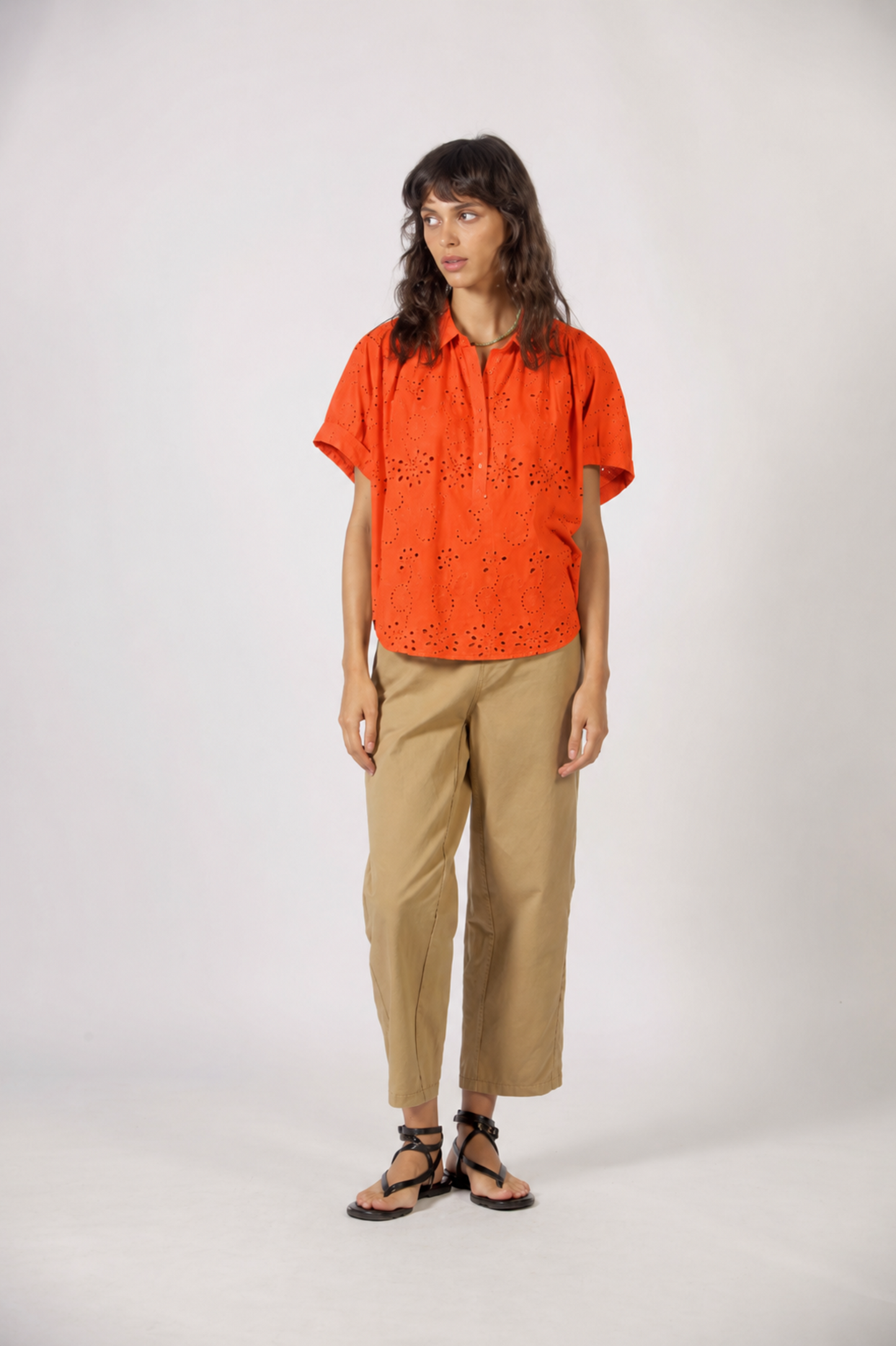 Haut Molly orange porté non rentré avec coupe fluide, manches amples et détails ajourés.