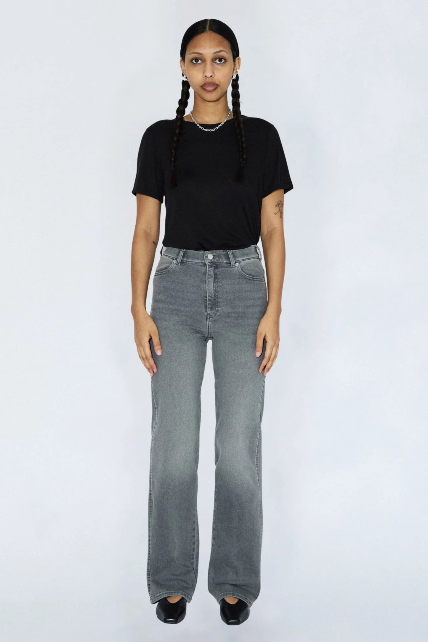 Femme portant le jeans Moxy gris clair avec un t-shirt noir, taille haute, jambe droite et style denim urbain.