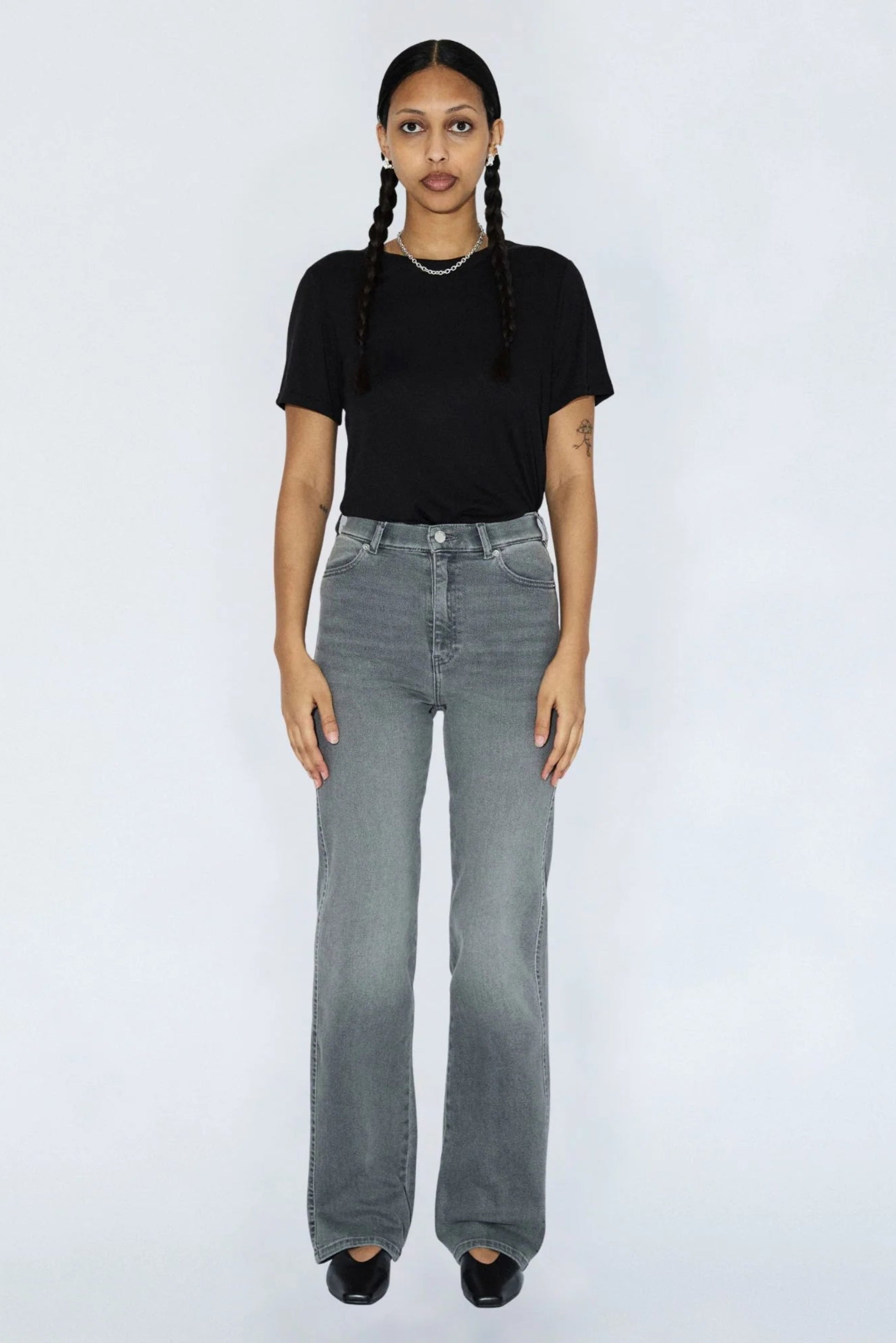 Femme portant le jeans Moxy gris clair avec un t-shirt noir, taille haute, jambe droite et style denim urbain.