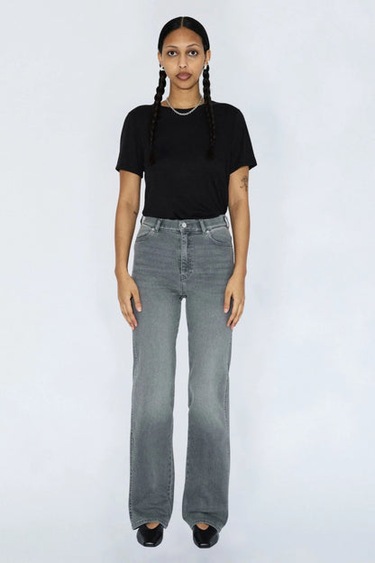 Femme portant le jeans Moxy gris clair avec un t-shirt noir, taille haute, jambe droite et style denim urbain.