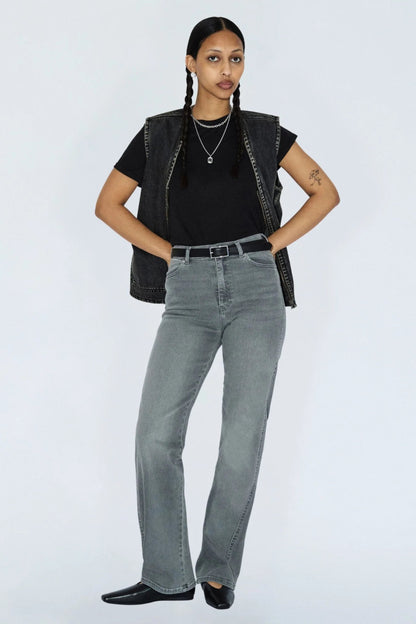 Jeans Moxy gris clair porté avec un haut noir et une veste sans manches en denim, coupe droite et style tendance.