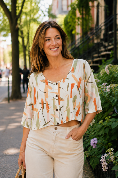 Blouse Nao Orange portée avec pantalon clair, imprimé abstrait orangé et boutons sur le devant.