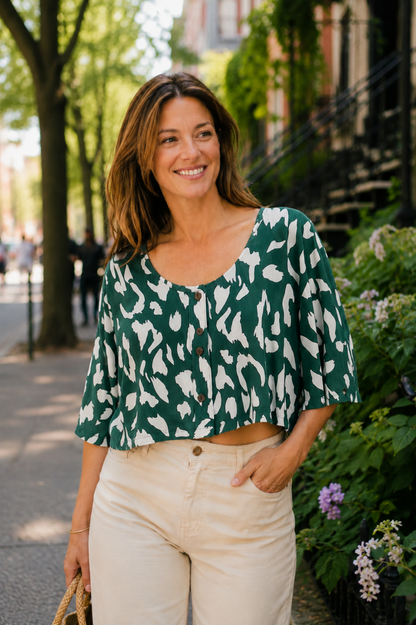 Blouse Nao Vert portée avec pantalon clair, imprimé abstrait blanc et boutons sur le devant.