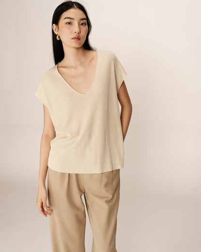 Zoom sur le col V du haut en maille lurex beige port avec un pantalon beige