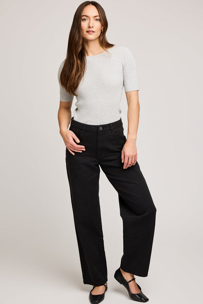 Pantalon noir porté avec un haut gris ajusté pour une silhouette moderne et épurée