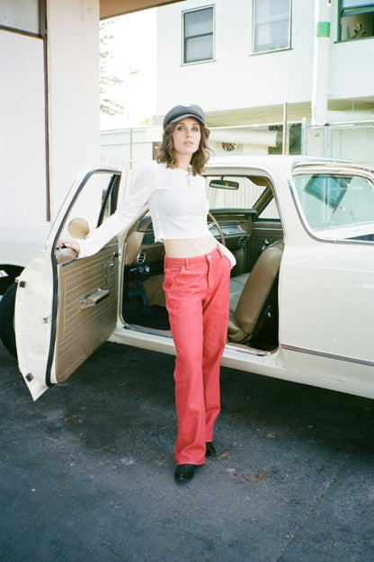 pantalon rouge brique porté avec un haut court blanc et une casquette grise